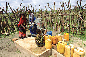 Frauen pumpen Wasser am neuen Brunnen.