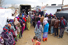 Frauen (links) und Männer (rechts) stehen schlange vor einem Lastwagen mit Hilfsgütern.